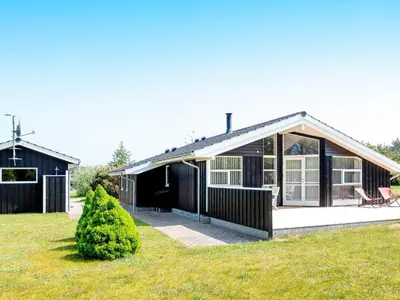 a black and white house with a yard at 6 person holiday home in Løkken in Løkken