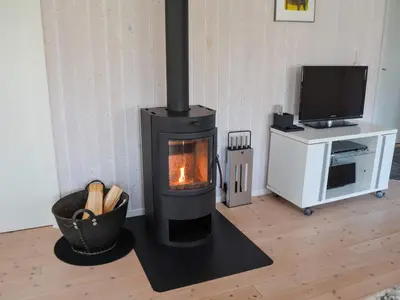 a wood stove in a living room with a television at 6 person holiday home in Løkken in Løkken