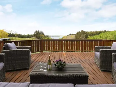 a deck with a table with a bottle of wine at 8 person holiday home in Skals in Skals
