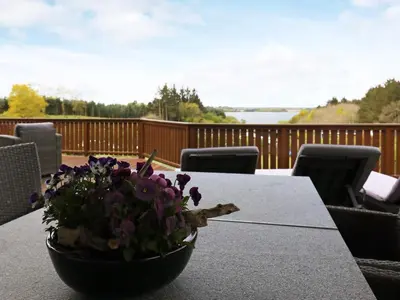 a table with a bowl of flowers on a deck at 8 person holiday home in Skals in Skals