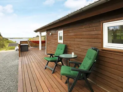 a wooden deck with four chairs and a table at 8 person holiday home in Skals in Skals