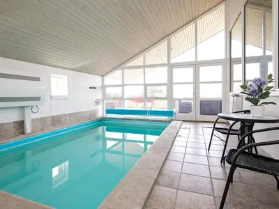 a large swimming pool with a table and chairs and a tablektop at 8 person holiday home in Skals in Skals