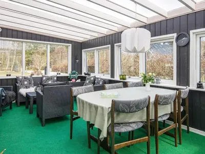 a dining room with a table and chairs and windows at Secluded Forest Haven-By Traum in Løgsted