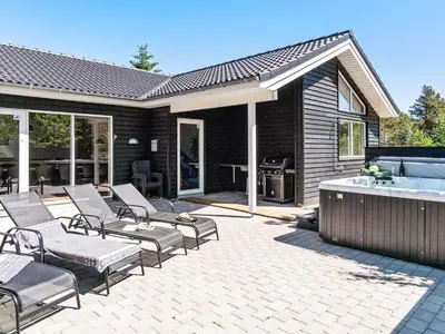 a patio with chairs and a hot tub next to a house at 18 person holiday home in Fjerritslev in Fjerritslev