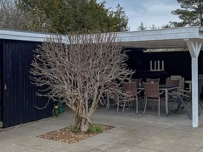 a tree in a patio with a table and chairs at 6 person holiday home in Brovst in Brovst