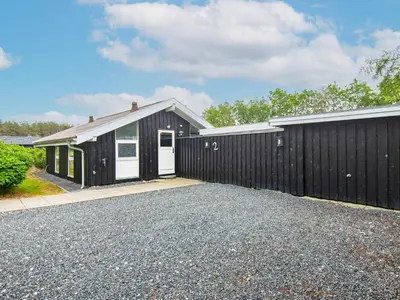 a house with a black fence and a driveway at 6 person holiday home in Brovst in Brovst