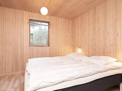 a bedroom with a white bed in a wooden wall at 6 person holiday home in Fjerritslev in Fjerritslev