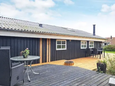 a backyard deck with a table and a house at Cozy Coastal Retreat in Gronhoj-By Traum in Løkken