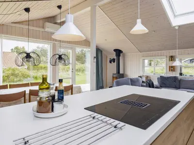 a kitchen and living room with a table with two bottles at Cozy Coastal Retreat in Gronhoj-By Traum in Løkken