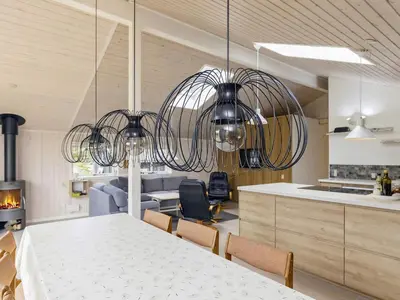 a kitchen and dining room with a table and chandelier at Cozy Coastal Retreat in Gronhoj-By Traum in Løkken