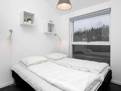 a white bedroom with a bed and a window at 6 person holiday home in Løkken in Løkken