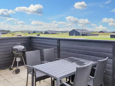 a table and chairs on a balcony with a grill at 6 person holiday home in Løkken in Løkken