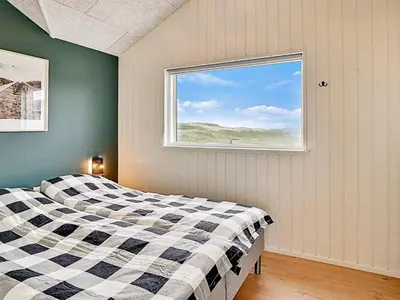 a bedroom with a checkered bed and a window at 10 person holiday home in Løkken in Løkken
