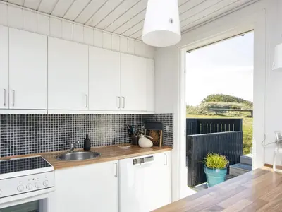 a kitchen with white cabinets and a large window at Family Holiday Home by North Sea in Lemvig