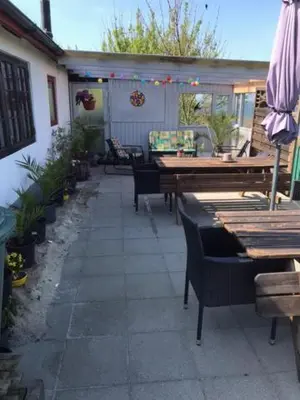 an outdoor patio with tables and chairs and an umbrella at KristiansBorg in Nykøbing Mors
