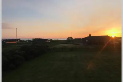 a sunset in a field with the sun setting at Beautiful and amazing view - 3 bedroom cottage in Vinderup
