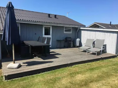 a wooden deck with a table and chairs and an umbrella at Beautiful and amazing view - 3 bedroom cottage in Vinderup