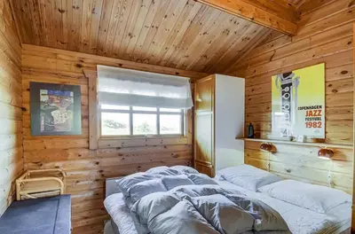 a bedroom with wooden walls with two beds in it at Cozy house with stunning sea views in Pandrup