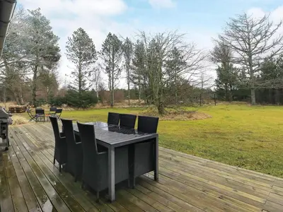 a table and chairs on a deck with a field at 6 person holiday home in Blokhus in Blokhus