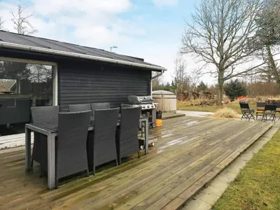 a patio with chairs and a grill on a deck at 6 person holiday home in Blokhus in Blokhus
