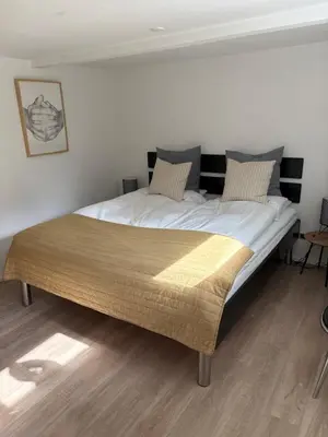 a large bed in a bedroom with a wooden floor at Nyistandsat højloftet kælderlejlighed på 70 m2 i Viborg centrum, med plads til 4 personer in Viborg