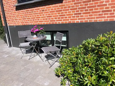 a table with two chairs and a vase with flowers on it at Nyistandsat højloftet kælderlejlighed på 70 m2 i Viborg centrum, med plads til 4 personer in Viborg