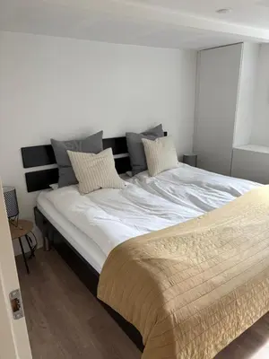 a bedroom with a large bed with white sheets and pillows at Nyistandsat højloftet kælderlejlighed på 70 m2 i Viborg centrum, med plads til 4 personer in Viborg