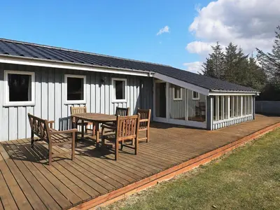 a deck with a table and chairs on a house at 8 person holiday home in Løkken in Løkken