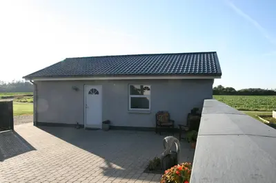a small white house with a patio in front at Hellerup Bed & Breakfast in Løgstrup