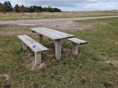 a wooden bench sitting in the grass next to a road at 6 person holiday home in Højslev-By Traum in Højslev