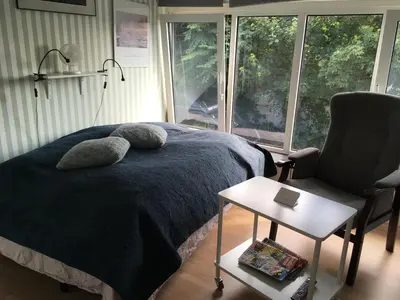 a bedroom with a bed and a chair and a window at Nationalpark Thy guesthouse in Vestervig