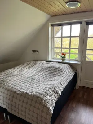 a bedroom with a bed and two windows at Kallerup Hgård in Thisted