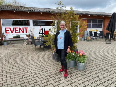 a woman standing in front of a house with flowers at Event4U in Nykøbing Mors