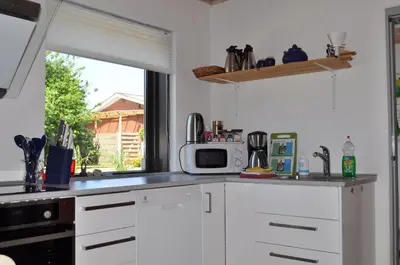 a kitchen with white cabinets and a microwave and a window at Event4U in Nykøbing Mors