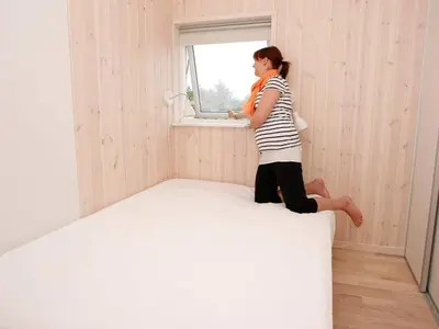 a woman sitting on a bed in a room with a window at Luxury Beach House in Blokhus - By Traum Ferienwohnungen in Blokhus