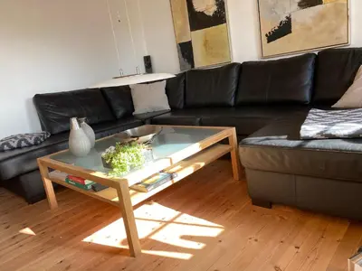 a living room with a black couch and a coffee table at A Vesterhav - tæt på 18b og hotel in Harboør