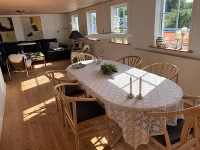 a dining room table with chairs and a living room at A Vesterhav - tæt på 18b og hotel in Harboør