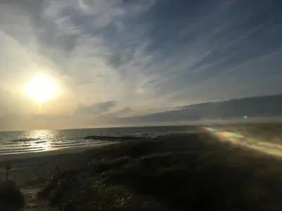 a sunset on the beach with the ocean at A Vesterhav - tæt på 18b og hotel in Harboør