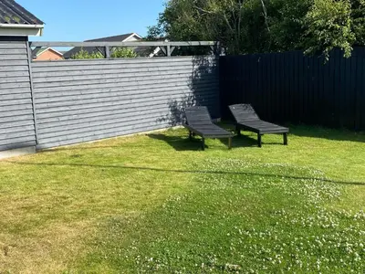 two benches sitting in a yard next to a fence at A Vesterhav - tæt på 18b og hotel in Harboør