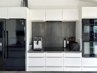 a kitchen with white cabinets and a black refrigerator at 10 person holiday home in Vinderup-By Traum in Vinderup