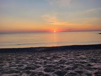 a beach with the sun setting over the water at Fiskerhuset in Agger