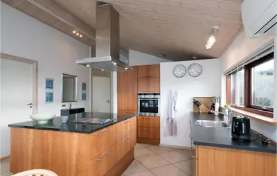 a kitchen with wooden cabinets and black counter tops at Holiday Home Ruthsvej in Løkken