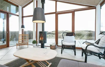 a living room with a table and chairs and a fireplace at Holiday Home Ruthsvej in Løkken
