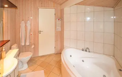 a bathroom with a tub and a toilet and a sink at Holiday Home Sarasvej Løkken in Løkken