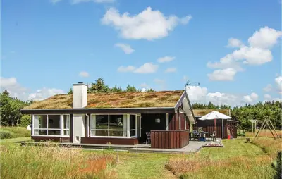 a small house with a grass roof on a field at Holiday Home Sarasvej Løkken in Løkken