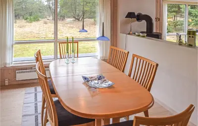 a wooden table and chairs in a kitchen with a window at Holiday Home Sarasvej Løkken in Løkken