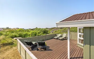 a deck with chairs and tables on top of a house at Holiday Home Porsevej Saltum in Saltum