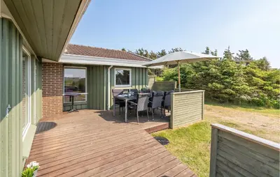 a wooden deck with a table and an umbrella at Holiday Home Porsevej Saltum in Saltum