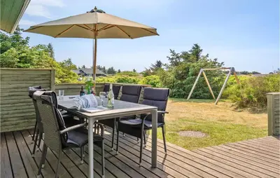 a table and chairs with an umbrella on a deck at Holiday Home Porsevej Saltum in Saltum