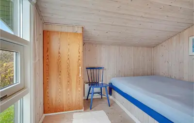 a small bedroom with a bed and a chair at Holiday Home Porsevej Saltum in Saltum
